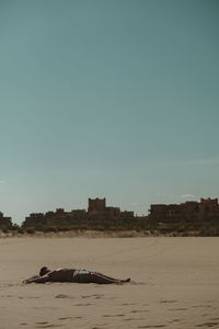 View of sleeping on beach against clear sky