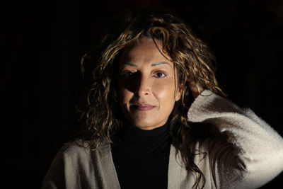 Close-up portrait of young woman against black background