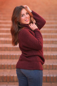 Portrait of smiling young woman standing against red background