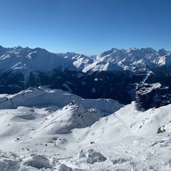 Scenic view of snow covered mountains against clear blue sky