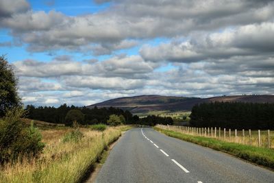 Surface level of country road against cloudy sky