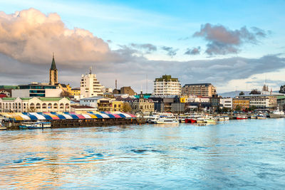 City at waterfront against cloudy sky