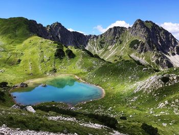 Scenic view of lake and mountains against blue sky