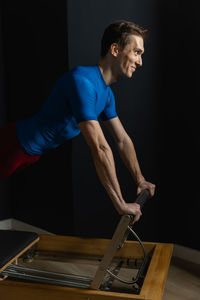 Side view of young man exercising in gym