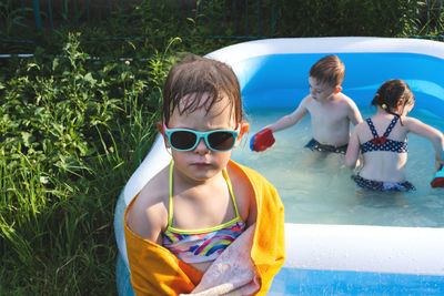 Wet and cheerful child in a towel and sunglasses near the pool. summer is a time of pleasure and fun