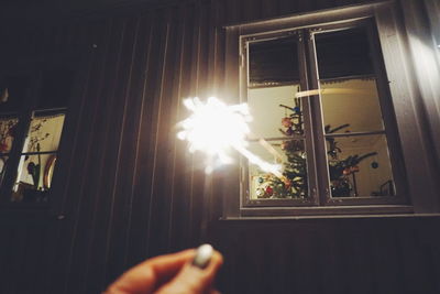 Low angle view of hand holding illuminated lamp at home