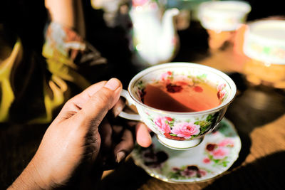 Cropped hand having tea in sunny day