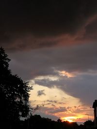 Low angle view of silhouette trees against dramatic sky