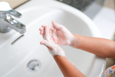 Cropped hand washing hands in sink