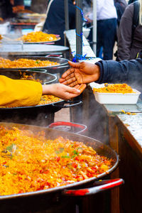 Hands meeting for a money exchange at an outdoor  market in london with street food including paella 