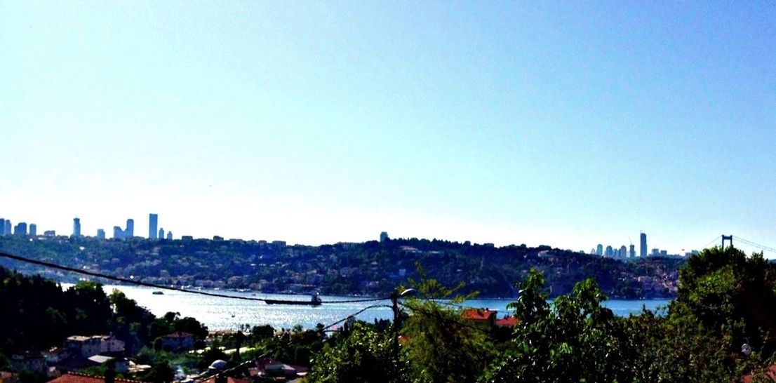 clear sky, copy space, architecture, built structure, city, water, building exterior, cityscape, blue, river, transportation, bridge - man made structure, tree, nautical vessel, sea, connection, high angle view, travel destinations, outdoors, capital cities