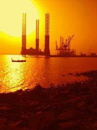 Silhouette of cranes at harbor during sunset