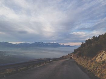 Country road against cloudy sky