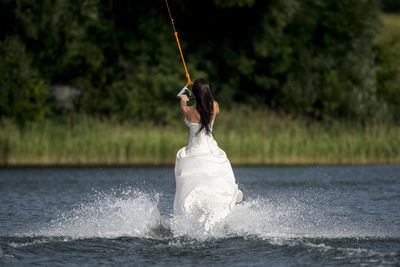 Woman wearing dress while kiteboarding in lake