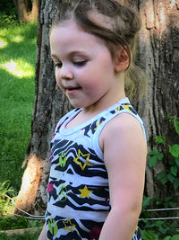 Low angle view of girl looking at tree trunk