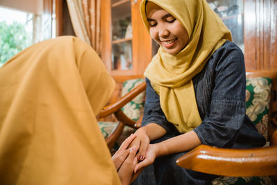 Portrait of young woman sitting on chair at home