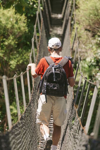 Rear view of man walking on footbridge