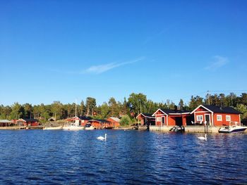 Scenic view of river by buildings against blue sky