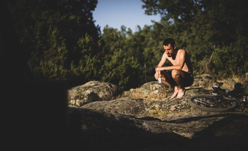 Man sitting on rock against trees
