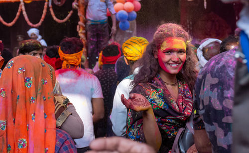 Portrait of smiling young woman with multi colored people in traditional clothing