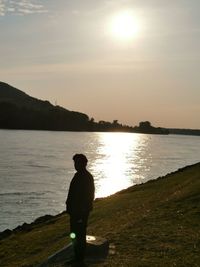 Rear view of silhouette man standing on beach during sunset