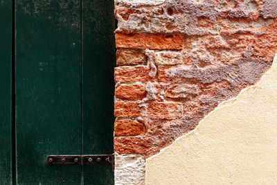 Close-up of old broken brick wall by door