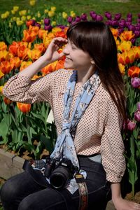 Young woman photographing with flowers