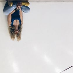 Upside down image of woman sitting against white wall