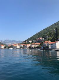 Town by sea against clear blue sky