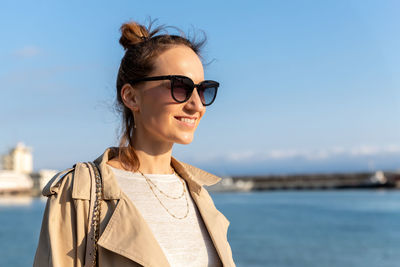 Portrait of young woman standing against sea