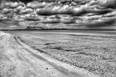 Scenic view of beach against cloudy sky