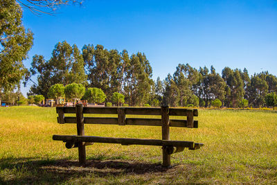 Park bench on field against clear sky