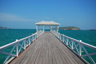 Pier over sea against clear blue sky