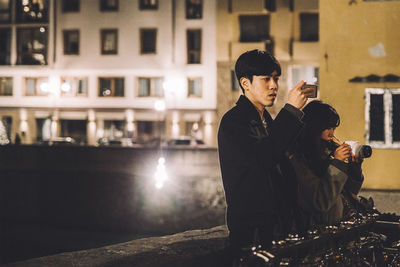 Man and woman standing in city at night