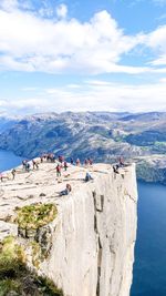 People on rock formation by sea against sky