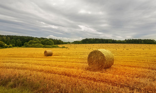 Hay bales on field against sky