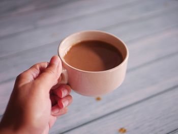 Cropped hand holding coffee on table