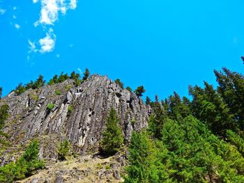 Low angle view of rocky mountains against blue sky