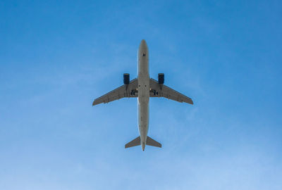 Low angle view of airplane against clear blue sky