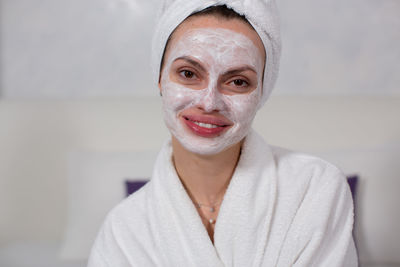 Young woman with facial mask on face at home