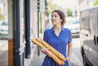 Young woman buying a french baguette