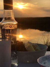 Close-up of glass bottle on table against sky during sunset