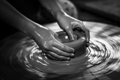 Cropped hands of person working on pottery wheel