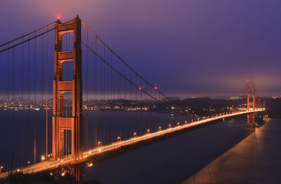 Suspension bridge over river at night