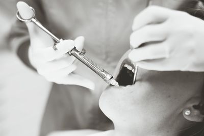 Close-up of dentist performing dental treatment on patient at clinic