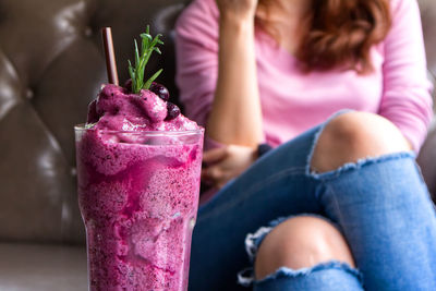 Close up blueberry smoothie on the table with background women sit on sofa.