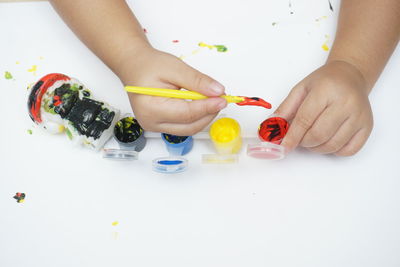 High angle view of woman hand holding multi colored pencils on table