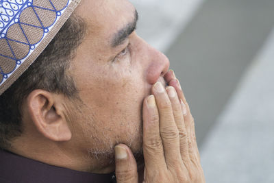 Close-up of mature man praying while sitting at mosque