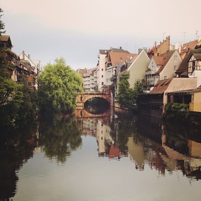 REFLECTION OF BUILDINGS IN WATER AGAINST SKY