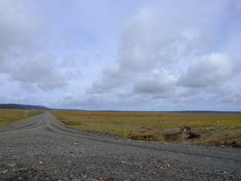 Road amidst field against sky